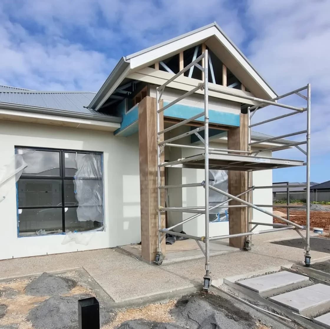 The entry portico part-built and scaffolded, with the gable clad