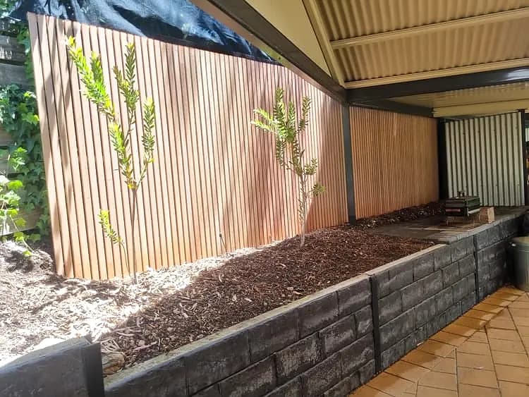 Finished slatted timber screen and garden wall beside a paved courtyard